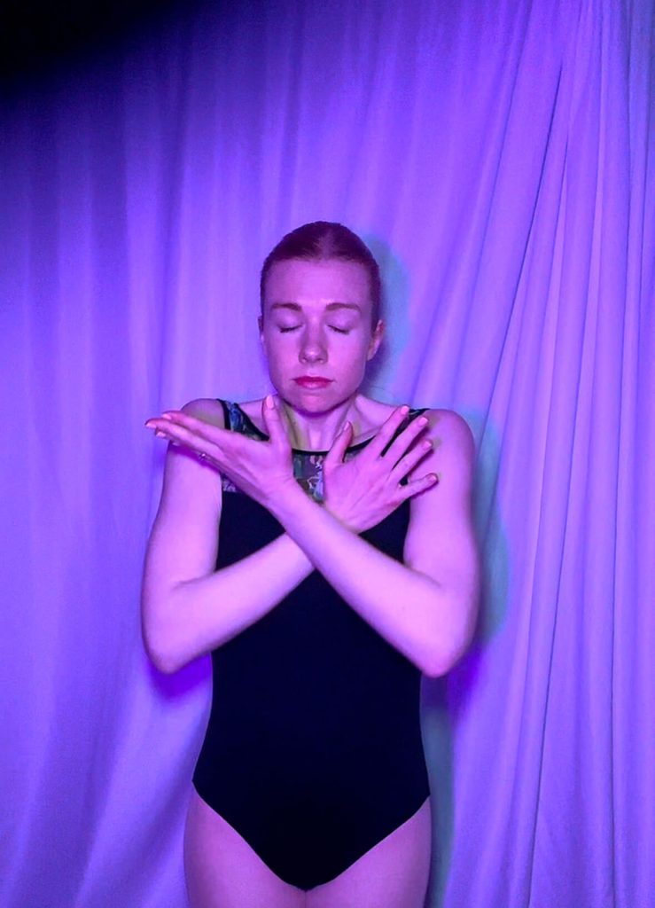 Susie Butler dances with her hands close to her face with an emotional expression of sadness