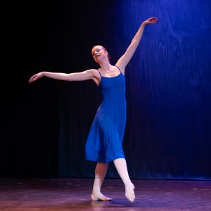 Susie Butler performs with emotion in a blue dress on stage
